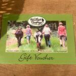 Photo of a paper gift voucher showing people and donkeys photographed from behind and sharing details of what's on offer