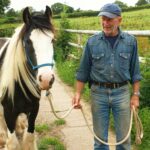 Photo of a man stood face-on for a photoshoot with a skewbald pony