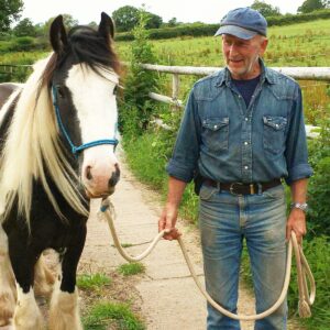 Photo of a man stood face-on for a photoshoot with a skewbald pony