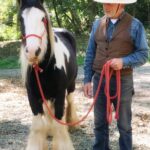 Photo of a man with a black and white pony looking at the camera