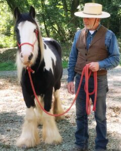 Photo of a man with a black and white pony looking at the camera